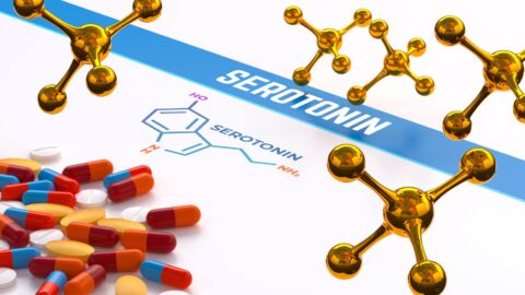 scattered pills on a flat surfaceNext to the pills, the text "SEROTONIN", accompanied by a molecular structure diagram representing serotonin's chemical composition representing the class of medications known as SSRIs.