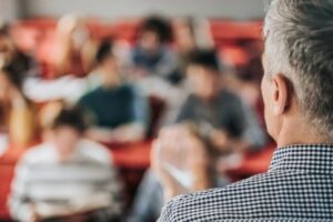 White male professor looks out into his students talking about depression diagnosis