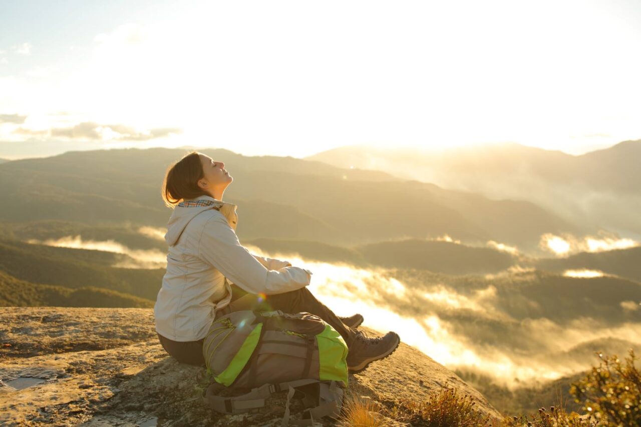 Young female hiker taking a break to breath in the fresh air as a mindfulness activity.